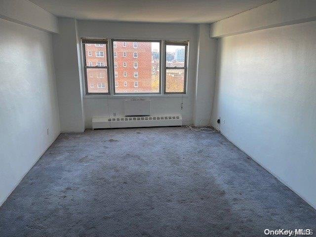 carpeted empty room with a baseboard radiator