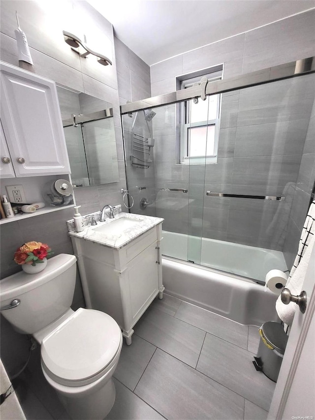 full bathroom featuring tile patterned flooring, vanity, toilet, and bath / shower combo with glass door