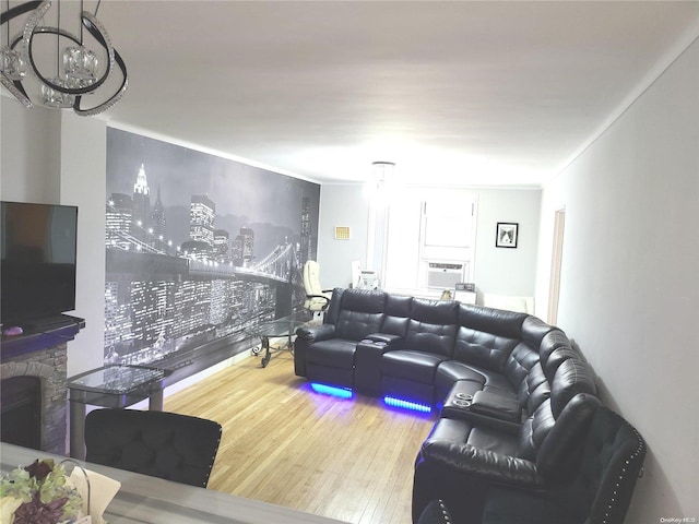 living room with cooling unit, wood-type flooring, a fireplace, and ornamental molding