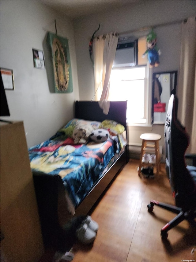 bedroom featuring a wall mounted AC and hardwood / wood-style floors