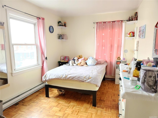 bedroom featuring multiple windows, light parquet floors, and a baseboard heating unit