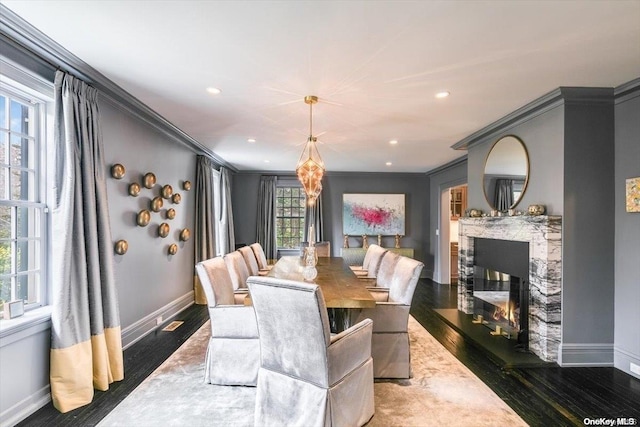 dining space featuring dark wood-type flooring, crown molding, and a healthy amount of sunlight