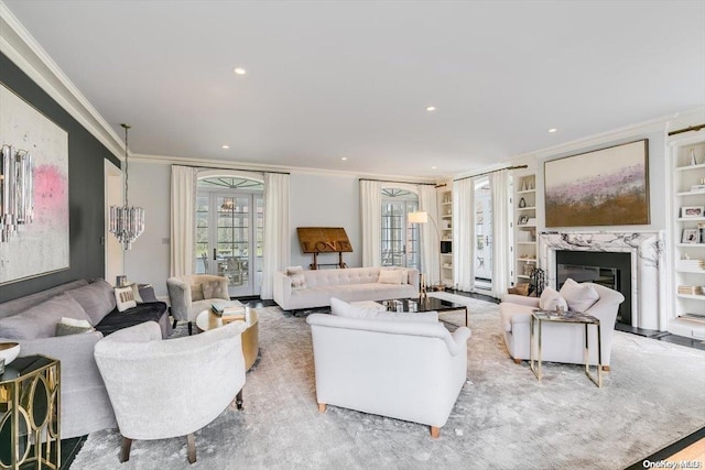 living room with a notable chandelier, built in shelves, a fireplace, and crown molding