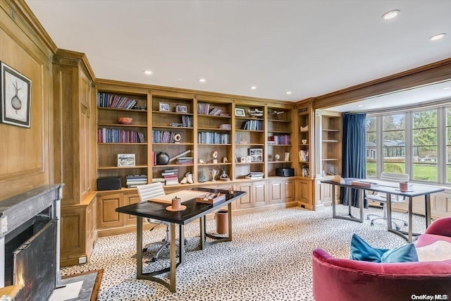 living area with built in shelves, light colored carpet, crown molding, and wooden walls