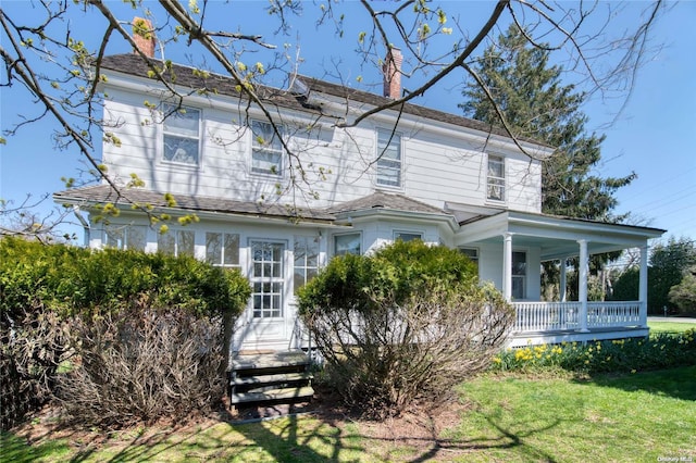 12115 Main Rd, East Marion, NY 11939 - view of front facade with a chimney, covered porch, and a front lawn