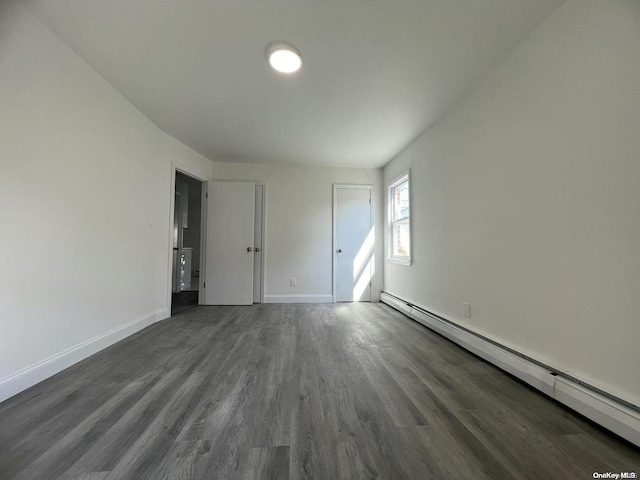 unfurnished room featuring dark wood-type flooring and a baseboard heating unit