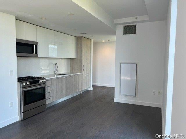 kitchen with white cabinetry, sink, dark wood-type flooring, and appliances with stainless steel finishes