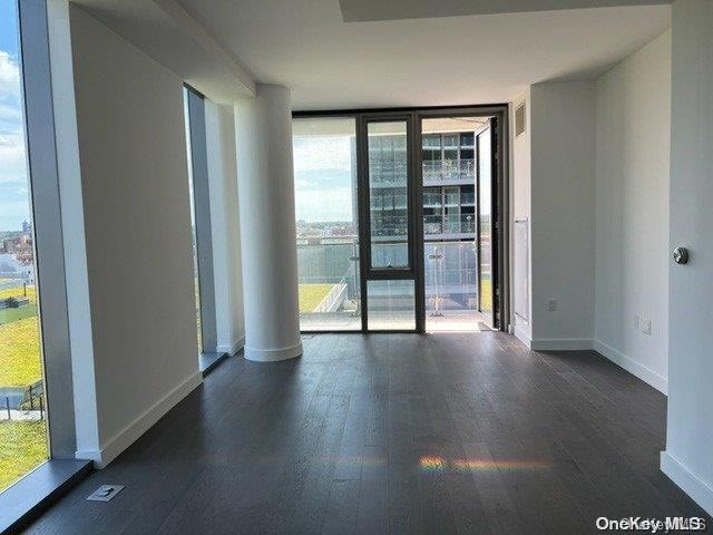 empty room with dark hardwood / wood-style flooring and floor to ceiling windows