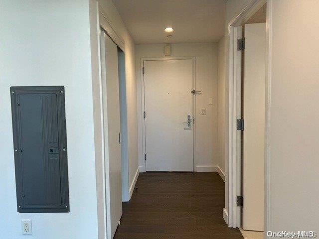 corridor with electric panel and dark hardwood / wood-style flooring