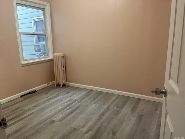 spare room featuring radiator, plenty of natural light, and light wood-type flooring