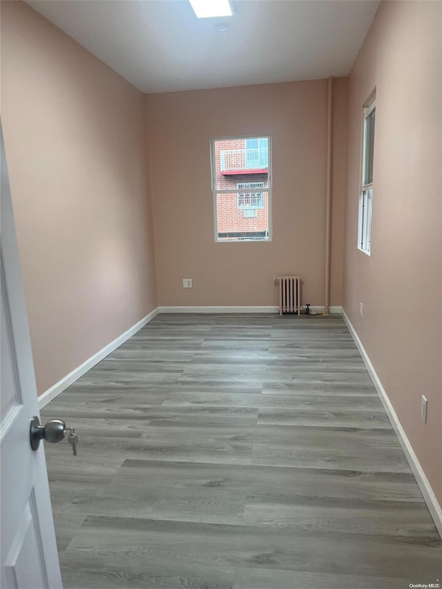 empty room with radiator heating unit, light wood-type flooring, and plenty of natural light