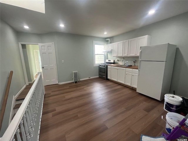 kitchen featuring gas range, white refrigerator, white cabinetry, and radiator heating unit