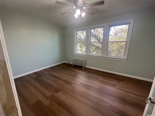 spare room featuring ceiling fan, radiator heating unit, and dark hardwood / wood-style floors