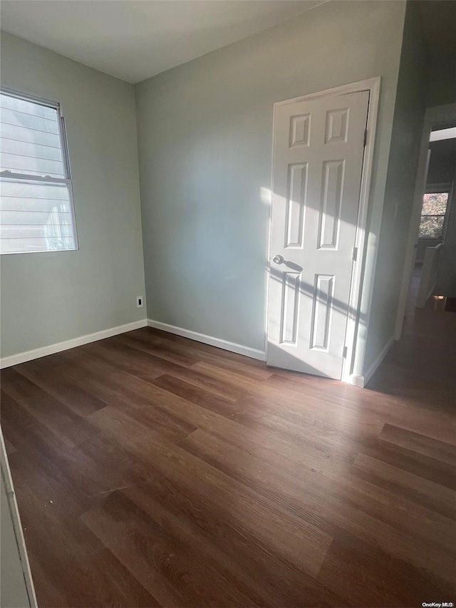 spare room featuring a healthy amount of sunlight and dark hardwood / wood-style floors