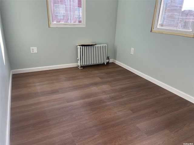 spare room with radiator heating unit and dark wood-type flooring