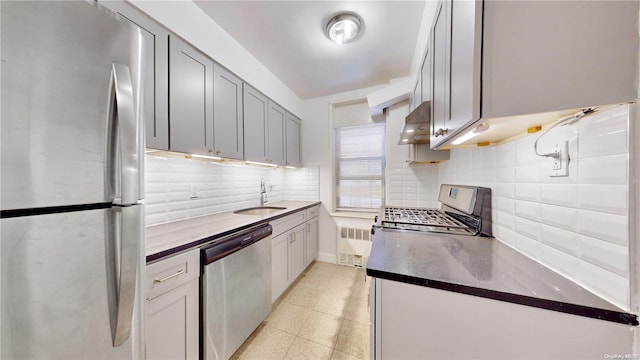 kitchen featuring sink, gray cabinets, tasteful backsplash, range hood, and appliances with stainless steel finishes