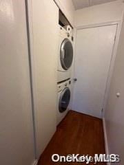 clothes washing area with stacked washing maching and dryer and dark hardwood / wood-style floors