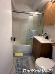 full bathroom with tile patterned flooring, vanity, tiled shower / bath combo, and toilet