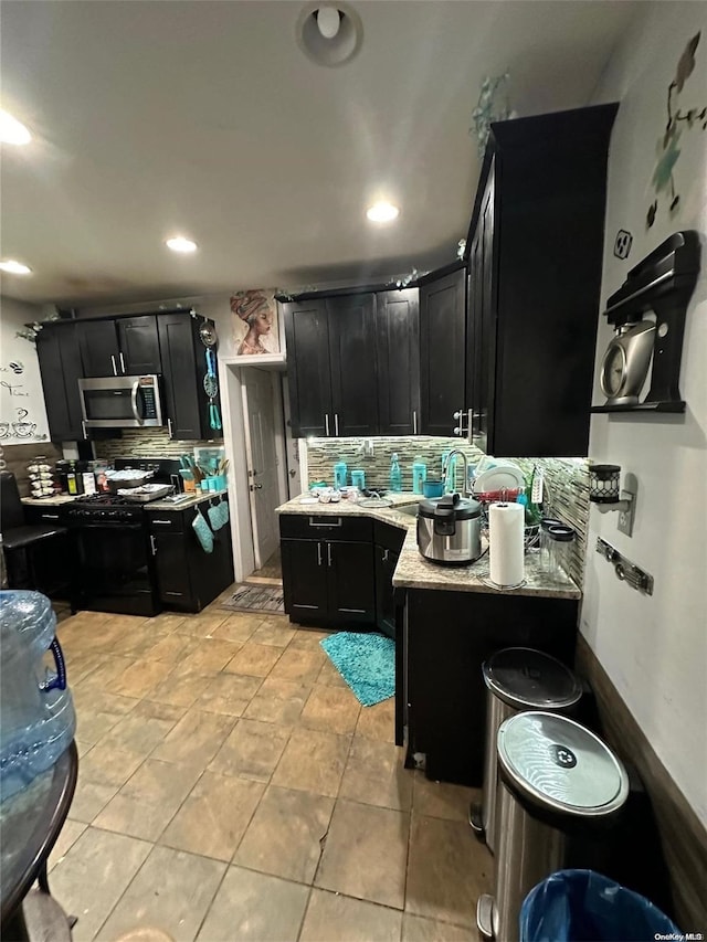 kitchen with light tile patterned floors, backsplash, light stone counters, and gas stove