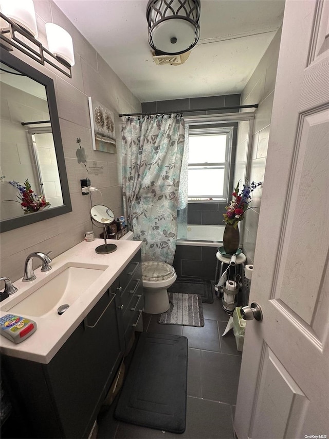 full bathroom with shower / tub combo, tile patterned floors, vanity, tile walls, and toilet