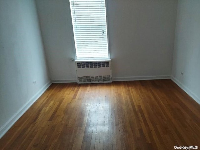 spare room featuring dark hardwood / wood-style flooring and radiator