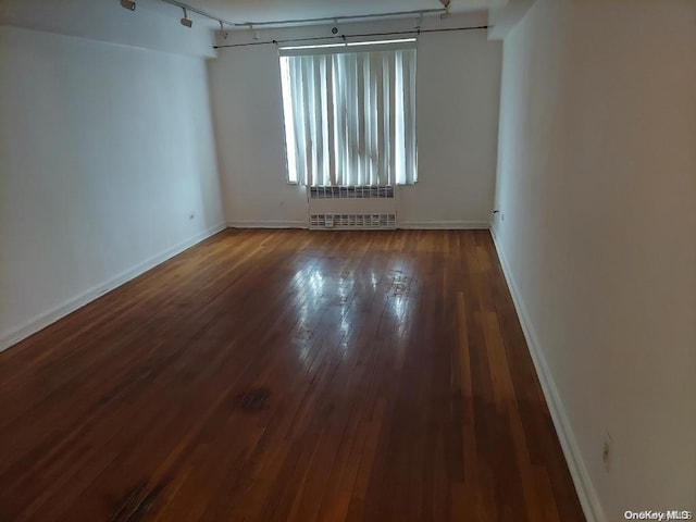 spare room featuring dark hardwood / wood-style flooring and radiator