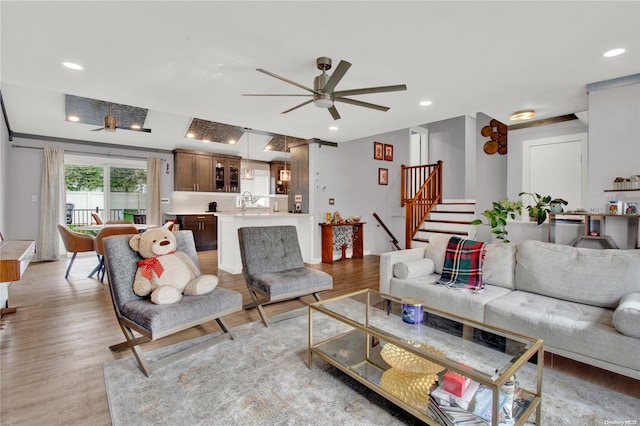 living room featuring light hardwood / wood-style flooring, ceiling fan, and sink