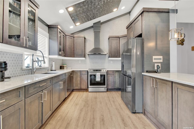 kitchen with wall chimney range hood, sink, decorative backsplash, light wood-type flooring, and appliances with stainless steel finishes