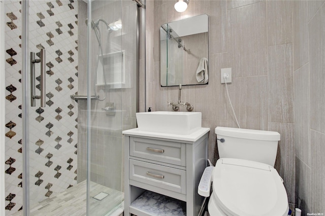 bathroom featuring vanity, toilet, a shower with shower door, and tile walls