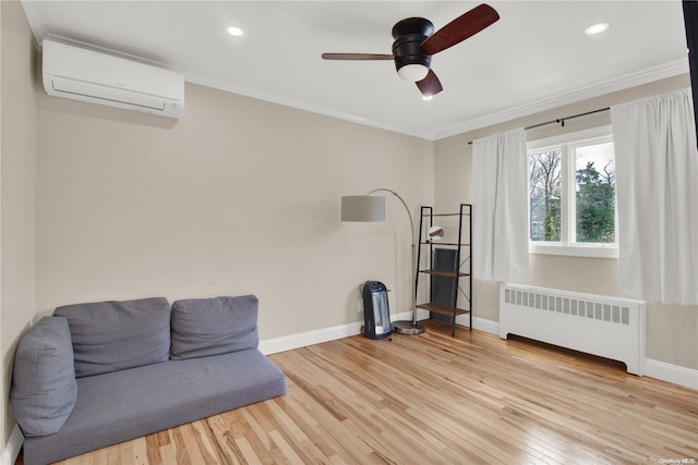 sitting room with radiator, crown molding, light hardwood / wood-style flooring, ceiling fan, and a wall mounted AC