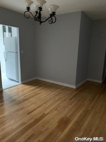 unfurnished dining area with wood-type flooring and an inviting chandelier