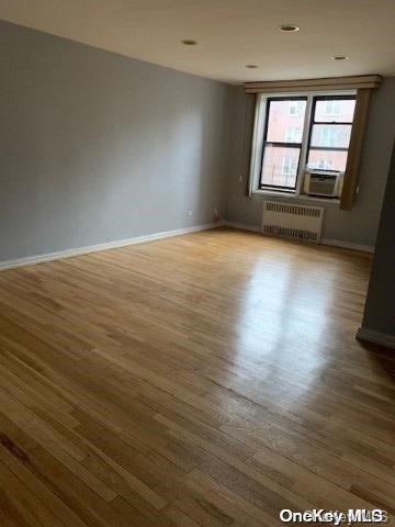 spare room with wood-type flooring, radiator, and cooling unit