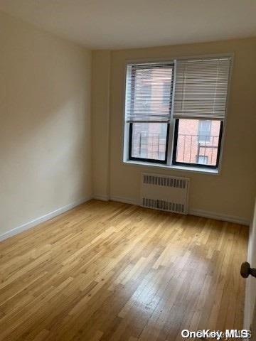 empty room with radiator and light hardwood / wood-style flooring