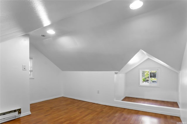 bonus room with hardwood / wood-style flooring, lofted ceiling, and a baseboard heating unit