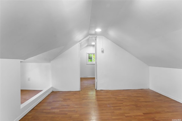 additional living space featuring wood-type flooring and lofted ceiling