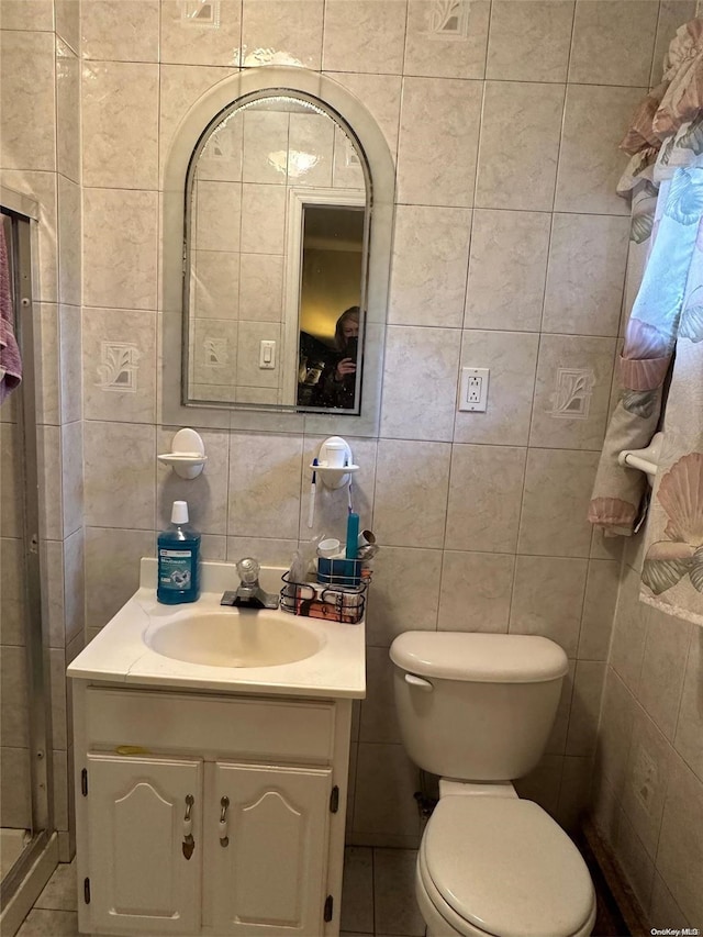 bathroom with vanity, toilet, and tile walls