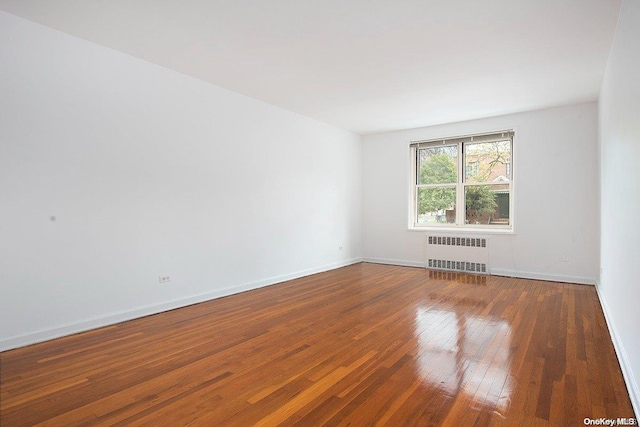 spare room featuring radiator heating unit and dark wood-type flooring