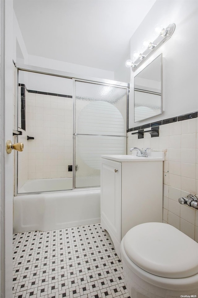 full bathroom with vanity, toilet, enclosed tub / shower combo, and tile walls