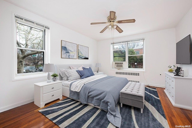 bedroom with radiator heating unit, dark hardwood / wood-style floors, and multiple windows