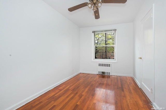 spare room featuring ceiling fan, radiator heating unit, and hardwood / wood-style flooring