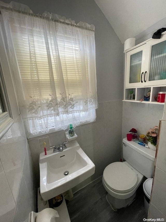 bathroom with lofted ceiling, sink, tile walls, and toilet