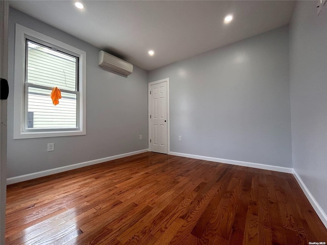 spare room with a wall mounted air conditioner and hardwood / wood-style flooring