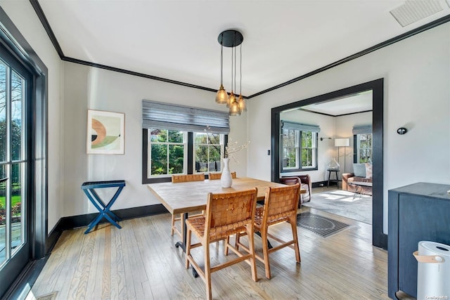 dining space with crown molding and light hardwood / wood-style flooring