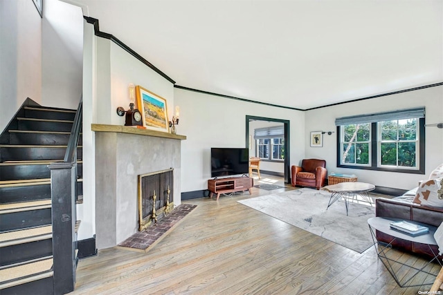 living room with a brick fireplace, ornamental molding, and light wood-type flooring