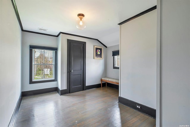 foyer entrance featuring hardwood / wood-style floors, lofted ceiling, and ornamental molding