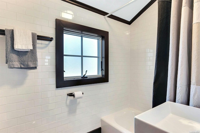 bathroom featuring shower / bath combination with curtain, tile walls, ornamental molding, and sink