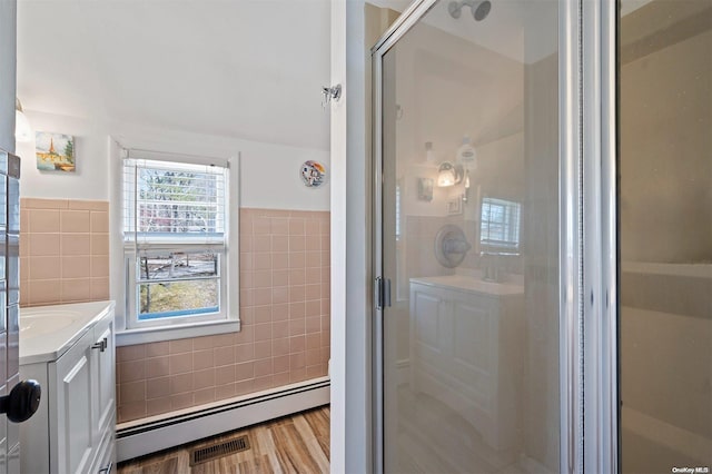 bathroom featuring tile walls, vanity, a baseboard radiator, and an enclosed shower