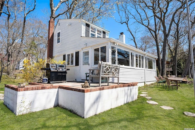 back of property with a sunroom and a lawn