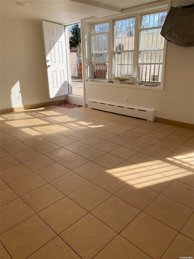 tiled empty room with a baseboard heating unit