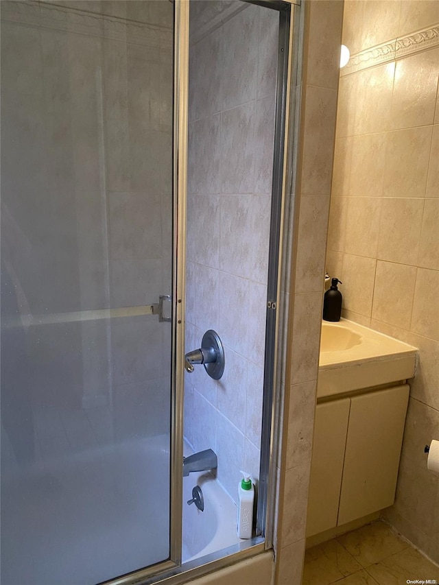 bathroom with vanity, enclosed tub / shower combo, and tile walls